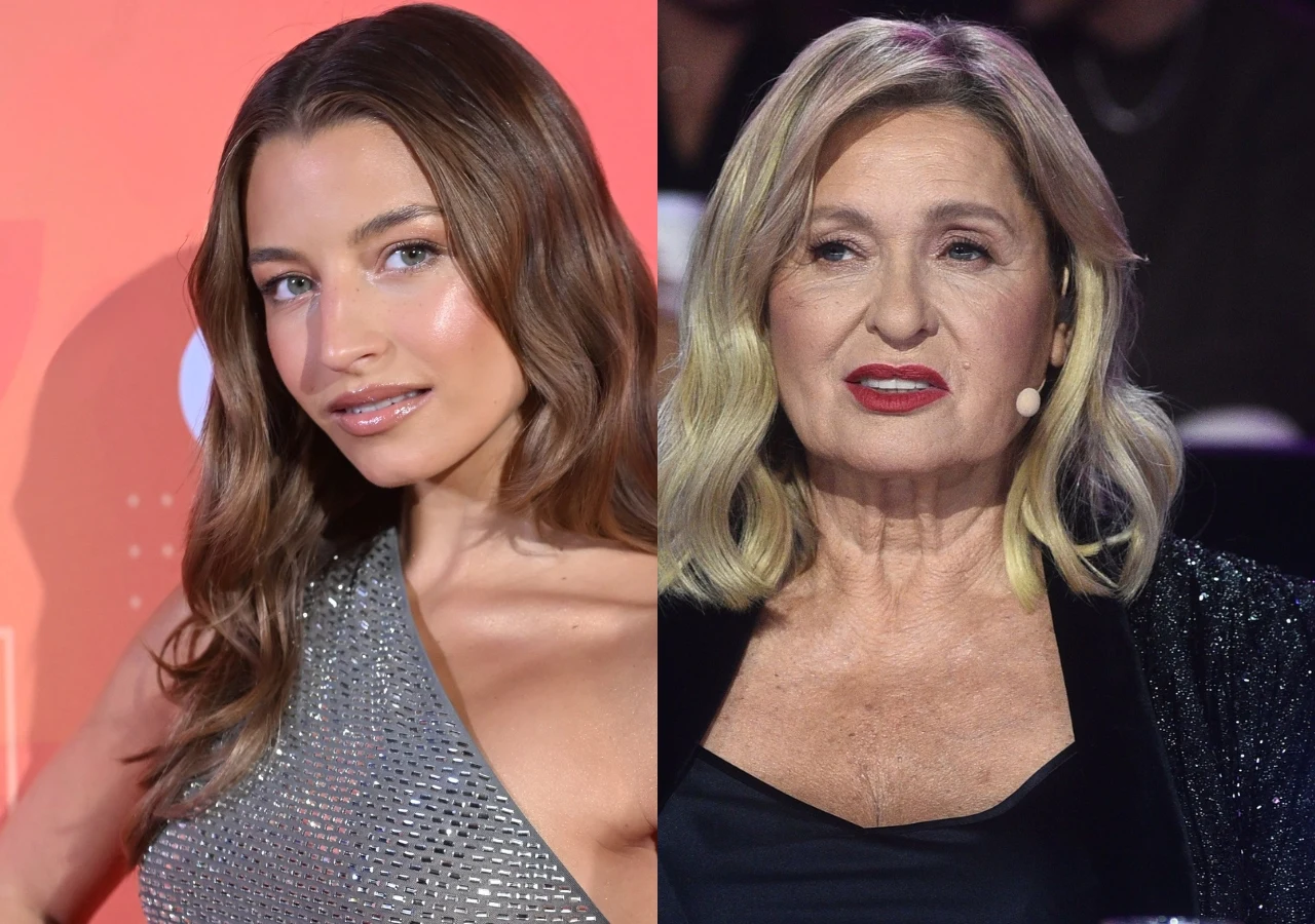Julia Wieniawa i Ewa Kasprzyk Dwie kobiety zwrócone w stronę obiektywu, jedna ubrana w błyszczącą srebrną sukienkę na tle w ciepłych kolorach, druga w ciemnej stylizacji, z mikrofonem nagłownym i starannym makijażem, na tle ciemniejszego wnętrza.