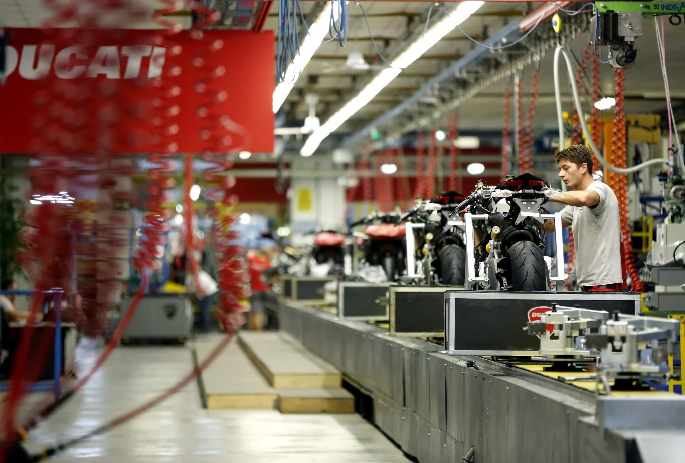 Ducati może trafić na sprzedaż Pracownik montuje motocykle Ducati na linii produkcyjnej w nowoczesnej hali fabrycznej