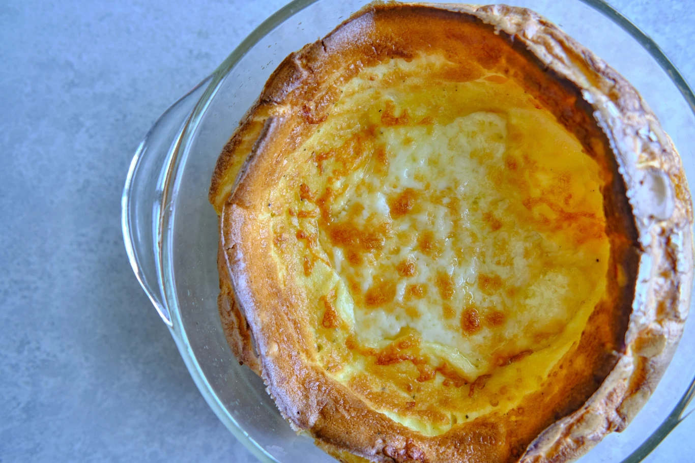 Dutch baby można przygotować w naczyniu żaroodpornym Złocisto przypieczony naleśnik pieczony w szklanym naczyniu z wyraźnie wyrośniętymi brzegami i lekko zarumienionym środkiem.