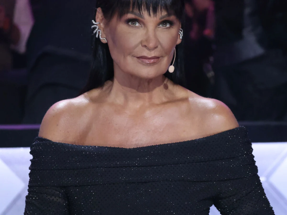 Iwona Pavlović Iwona Pavlović jako jurorka programu Taniec z gwiazdami, ubrana w czarną suknię, siedzi przy stole jurorskim.