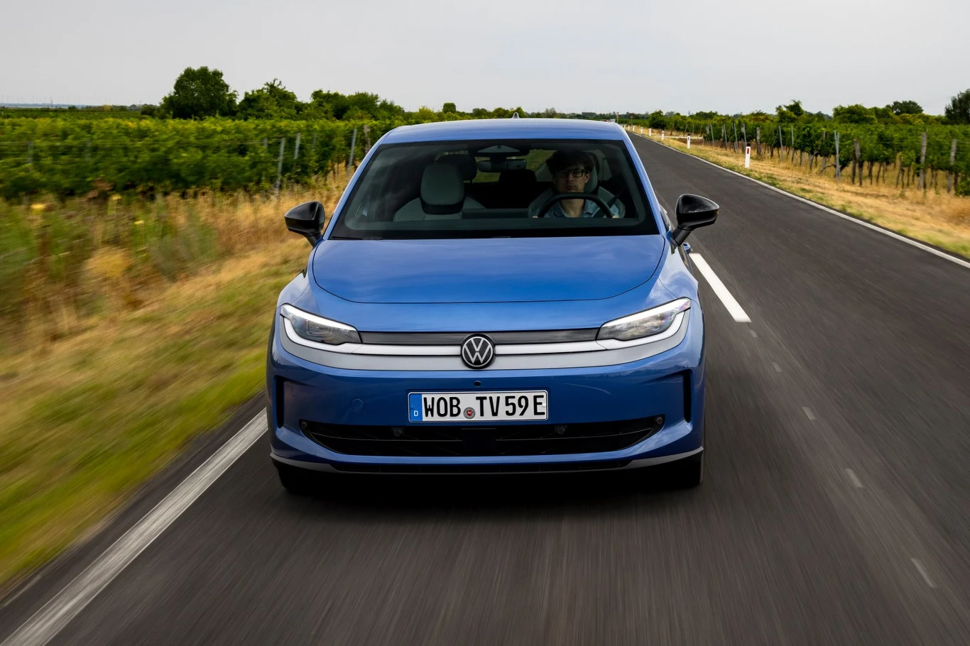 Niezależnie od nawierzchni ID. Polo dobrze radzi sobie z tłumieniem nierówności, co w tej klasie wcale nie jest oczywistością. Niebieski Volkswagen jedzie prostą, asfaltową drogą otoczoną zielonymi polami i roślinnością.