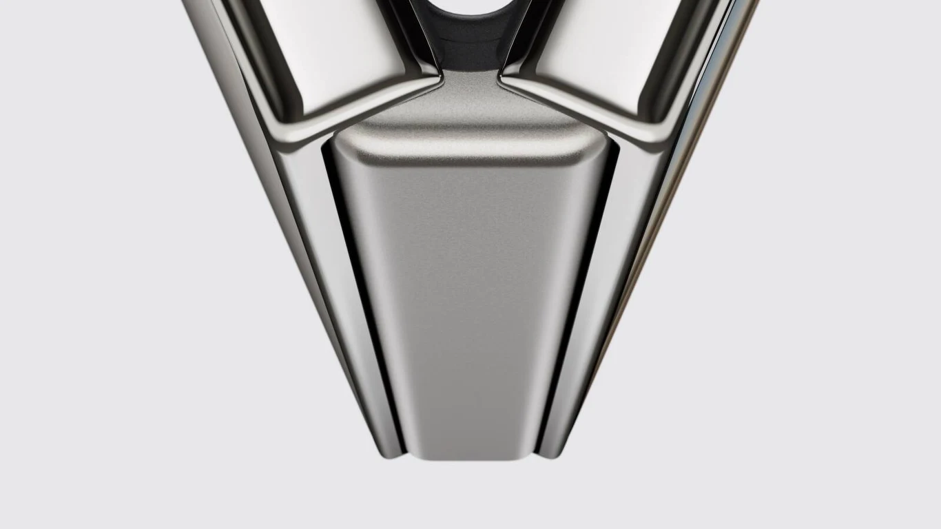 Chromowany, metaliczny element o geometrycznym, trójkątnym kształcie z wyraźnymi krawędziami i gładką powierzchnią, odbijający światło.