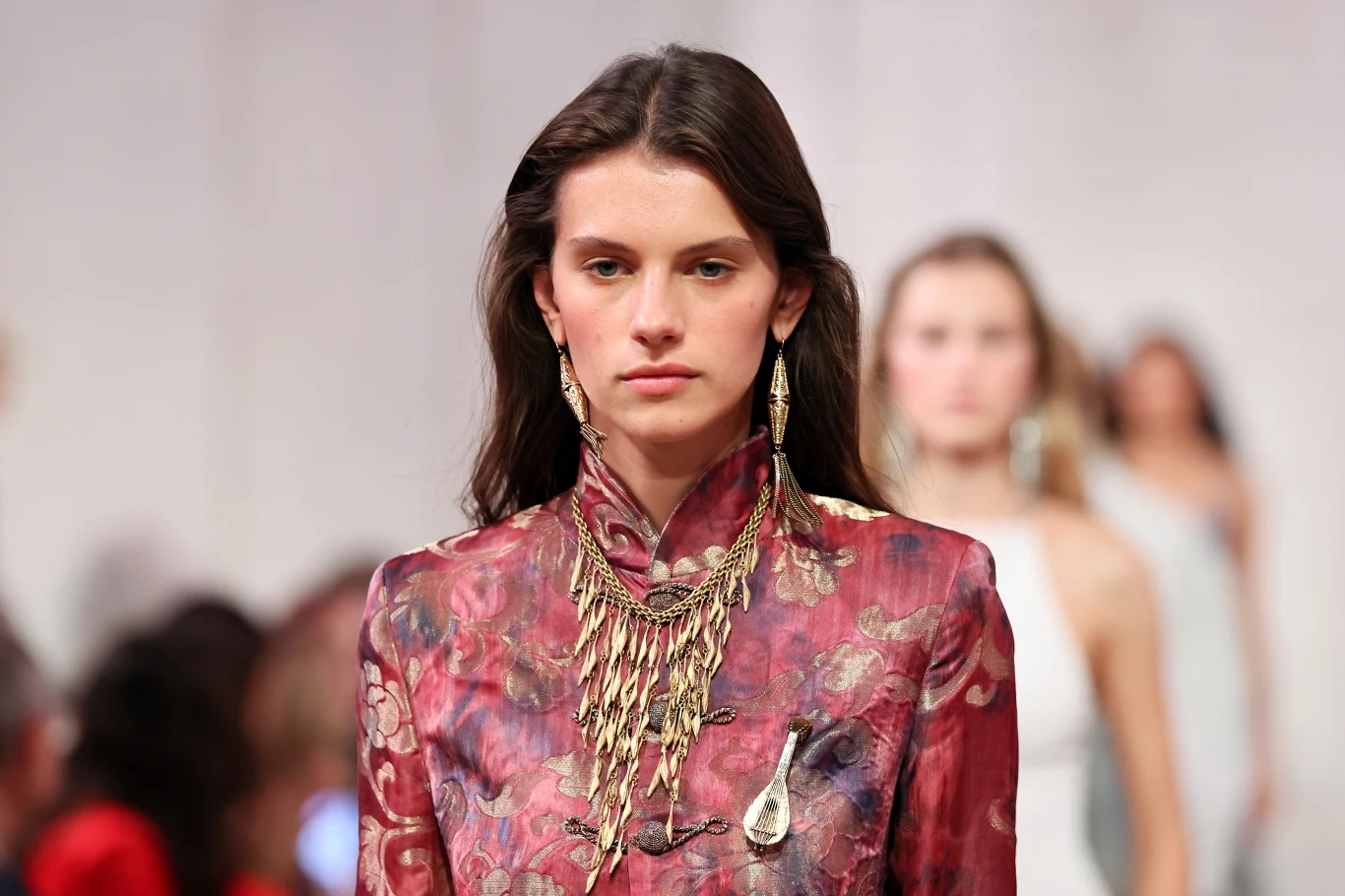 Ralph Lauren otworzył Tydzień Mody w Nowym Jorku Kobieta w bordowej sukni z kwiatowym wzorem i złotą biżuterią na wybiegu pokazu Ralpha Laurena.