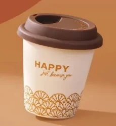 Biały kubek z brązową przykrywką, ozdobiony złotym napisem 'HAPPY just because you' oraz dekoracyjnym wzorem na dole.