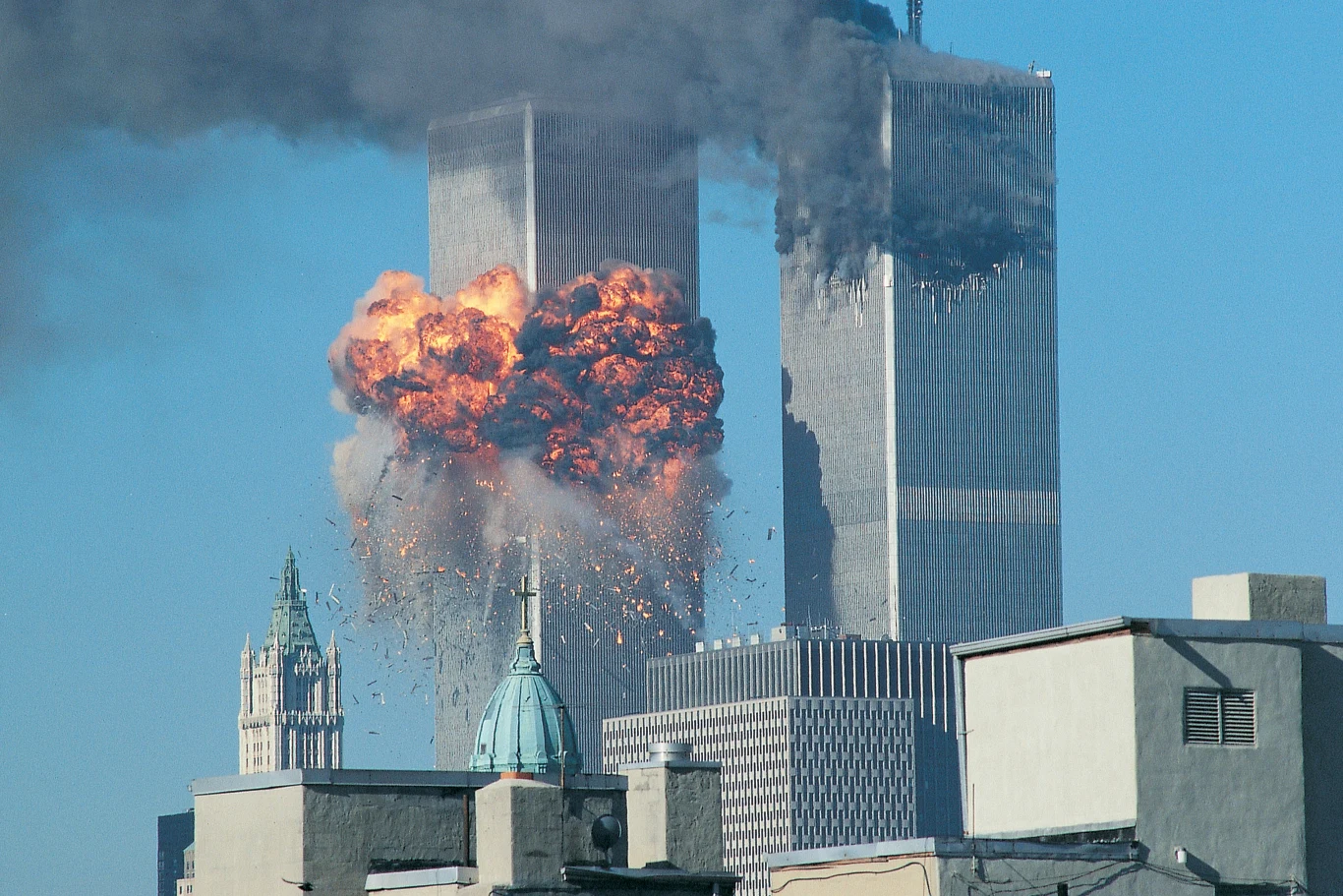 Zamachy z 11 września były wstrząsem dla całego zachodniego świata Dwie płonące wieże World Trade Center z eksplozją i kłębem czarnego dymu, otoczone nowojorskimi wieżowcami.