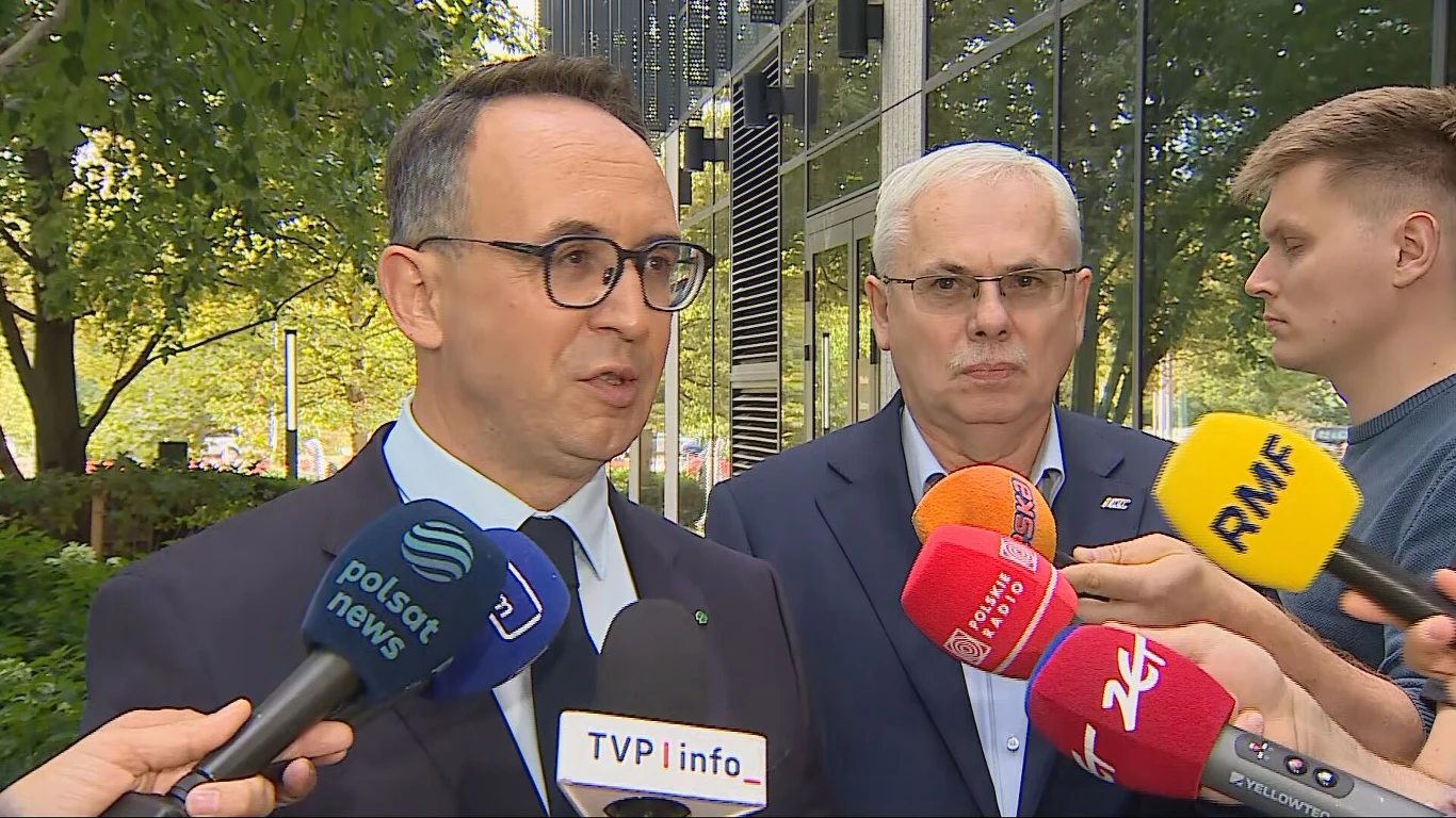 Minister infrastruktury Dariusz Klimczak podczas konferencji prasowej Minister Dariusz Klimczak i inny mężczyzna w garniturach podczas konferencji prasowej przed budynkiem