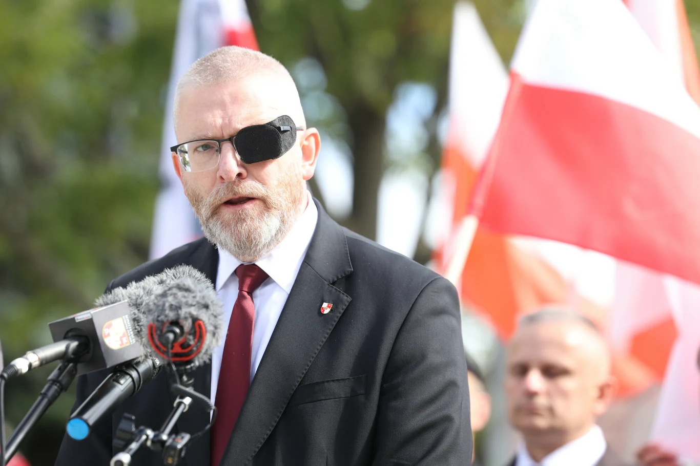 Grzegorz Braun zamieścił nagranie, na którym niszczy pomnik żołnierzy UPA Grzegorz Braun w garniturze i opasce na oku przemawia do mikrofonów, w tle polskie flagi i ludzie