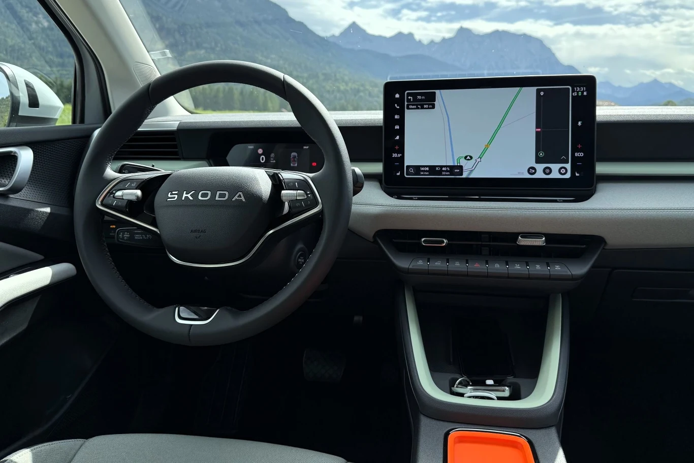 Kokpit samochodu Skoda z cyfrowym wyświetlaczem za kierownicą oraz dużym ekranem dotykowym z nawigacją pośrodku deski rozdzielczej.