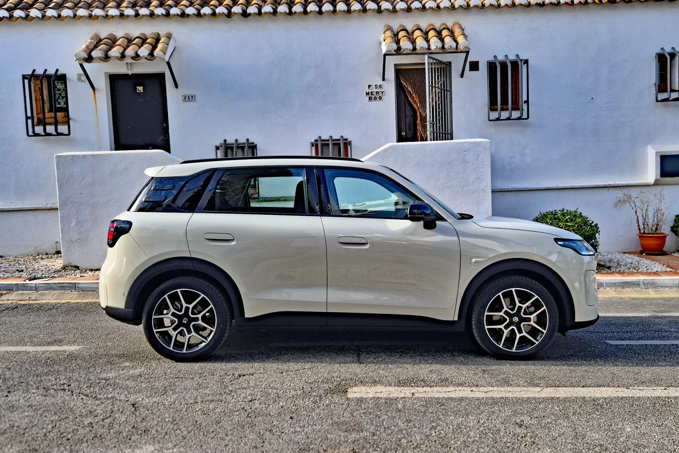 Leapmotor B03X Biały SUV zaparkowany przy ulicy na tle białego budynku z oknami zabezpieczonymi kratami i charakterystycznym dachówkami.