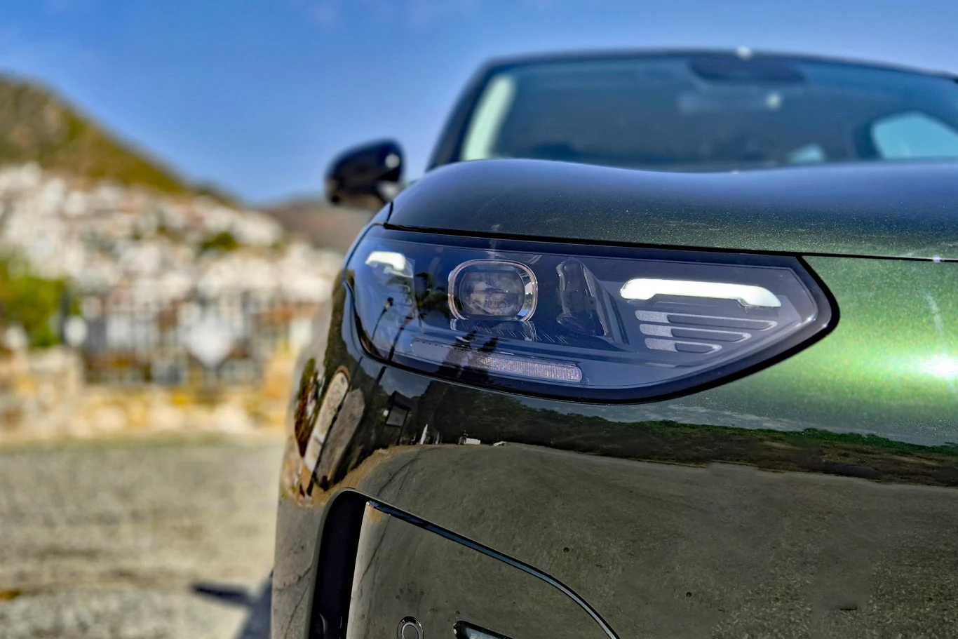 Leapmotor B03X Zbliżenie na reflektor nowoczesnego samochodu o ciemnozielonym lakierze, wyraźnie widoczne detale lampy i linie karoserii.