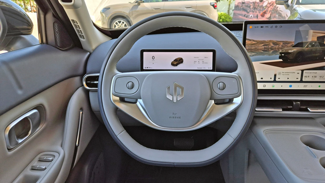 Leapmotor B03X Minimalistyczna kierownica samochodu elektrycznego z wbudowanym panelem cyfrowym za nią oraz dużym ekranem multimedialnym po prawej stronie.
