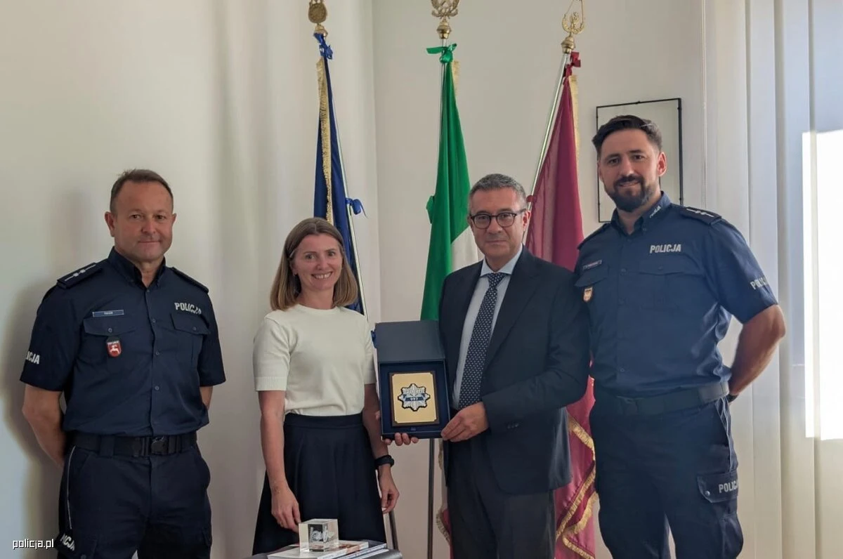 Tarnowski policjant wspierał zabezpieczenie Grand Prix Włoch na torze Monza Dwóch policjantów, kobieta i mężczyzna prezentujący pamiątkową plakietkę; w tle widoczne trzy flagi.