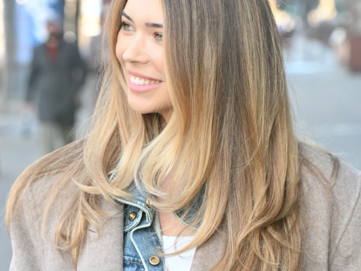 Sandra Kubicka Sandra Kubicka w beżowym płaszczu i jeansowej kurtce, uśmiechnięta, z rozpuszczonymi włosami.