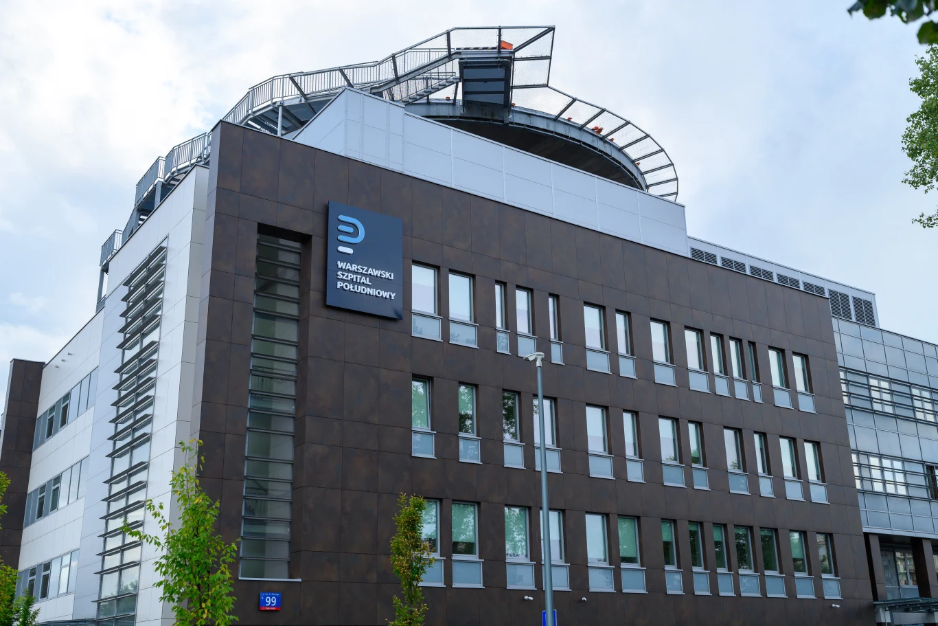 Warszawski Szpital Południowy (zdj. ilustracyjne) Warszawski Szpital Południowy, nowoczesny budynek z dużymi oknami i logotypem uczelni na elewacji.