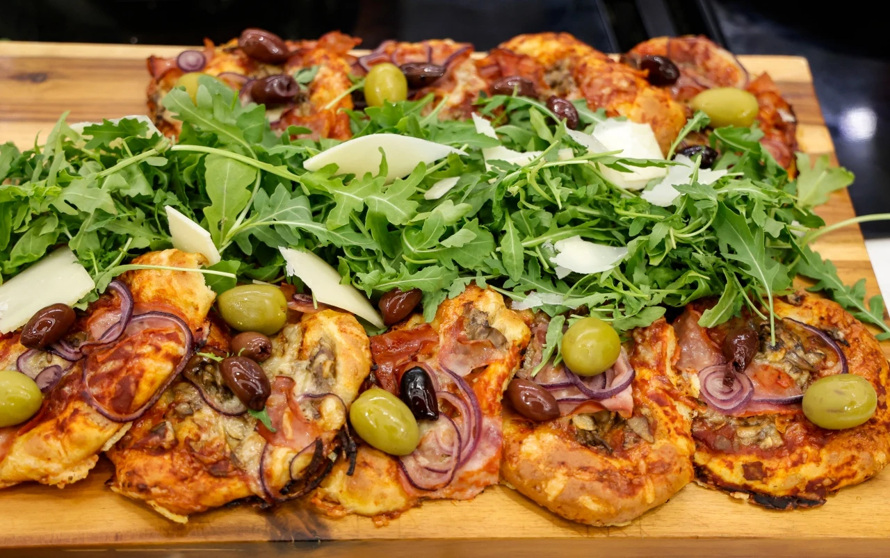 Ekspresowe pizzerinki z paprykowego serka Ekspresowe pizzerinki z paprykowego serka z cebulą, oliwkami, rukolą i płatkami sera na drewnianej desce
