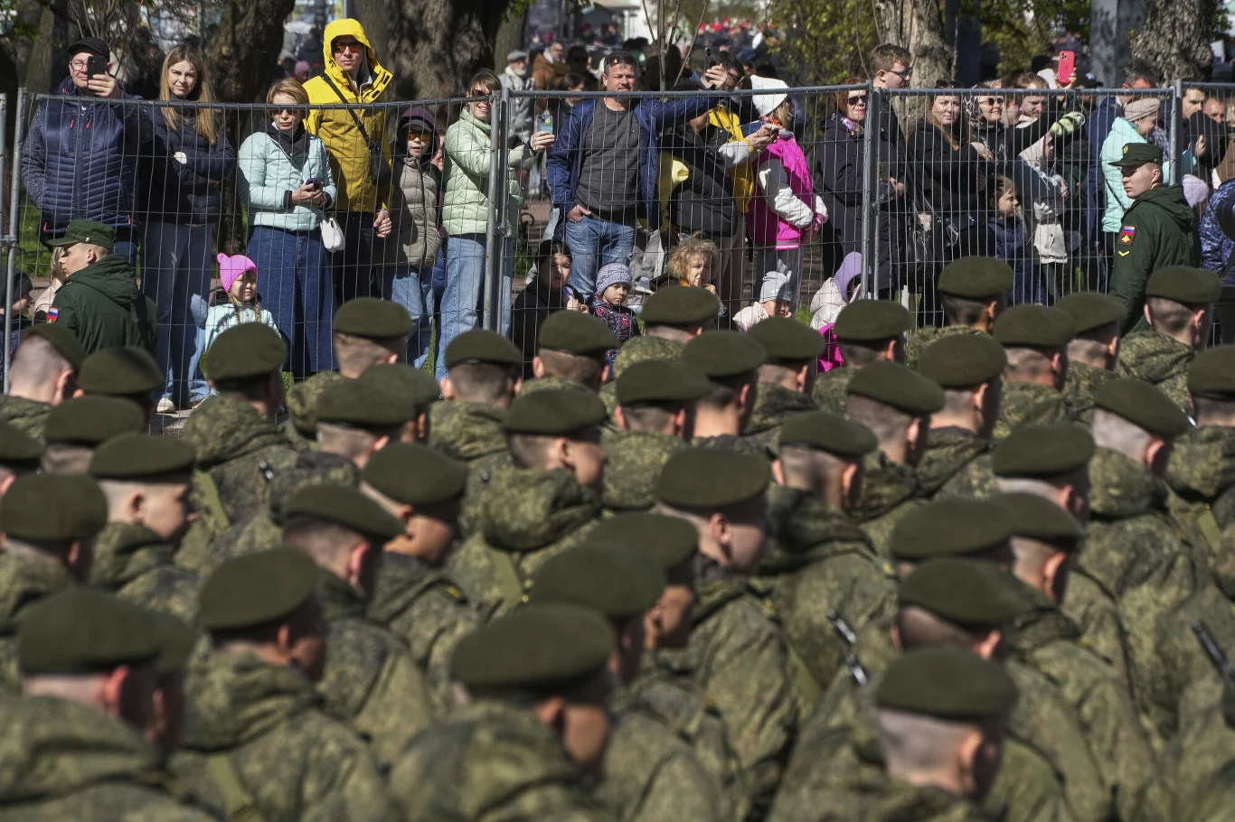 Obywatele państw azjatyckich mają trafiać na front w wyniku podstępu Rosji Szereg rosyjskich żołnierzy w zielonych mundurach przechodzi przed tłumem cywilów oddzielonych metalowym ogrodzeniem.