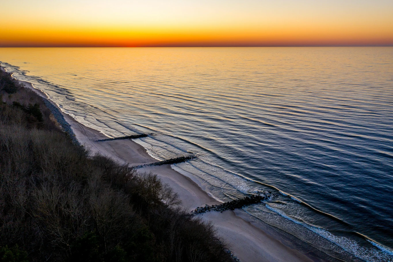 To najlepsza plaża na zachód słońca nad Bałtykiem. Spektakl co wieczór Zachód słońca nad plażą w Rewalu nad Bałtykiem, widok z klifu na morze i złocisty piasek.