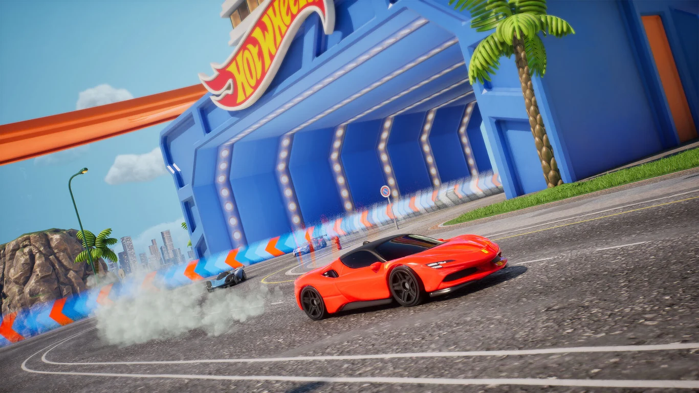 Czerwony sportowy samochód wykonuje efektowny poślizg na torze wyścigowym Hot Wheels, z niebiesko-pomarańczowym tunelem w tle oraz towarzyszącym mu dymem od opon.
