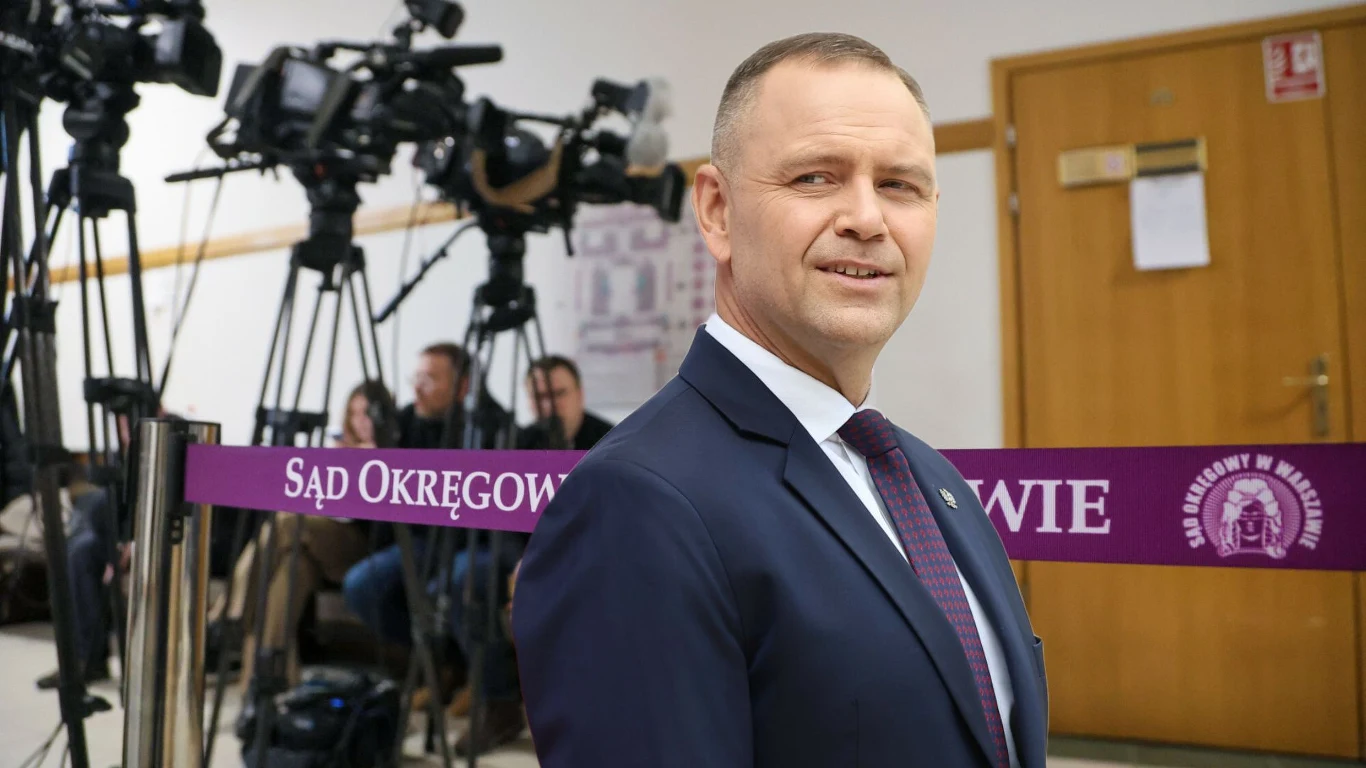 Karol Nawrocki pozwał wydawcę Onetu Karol Nawrocki w garniturze przed wejściem do sali sądowej, za taśmą 'Sąd Okręgowy', w tle kamery i dziennikarze
