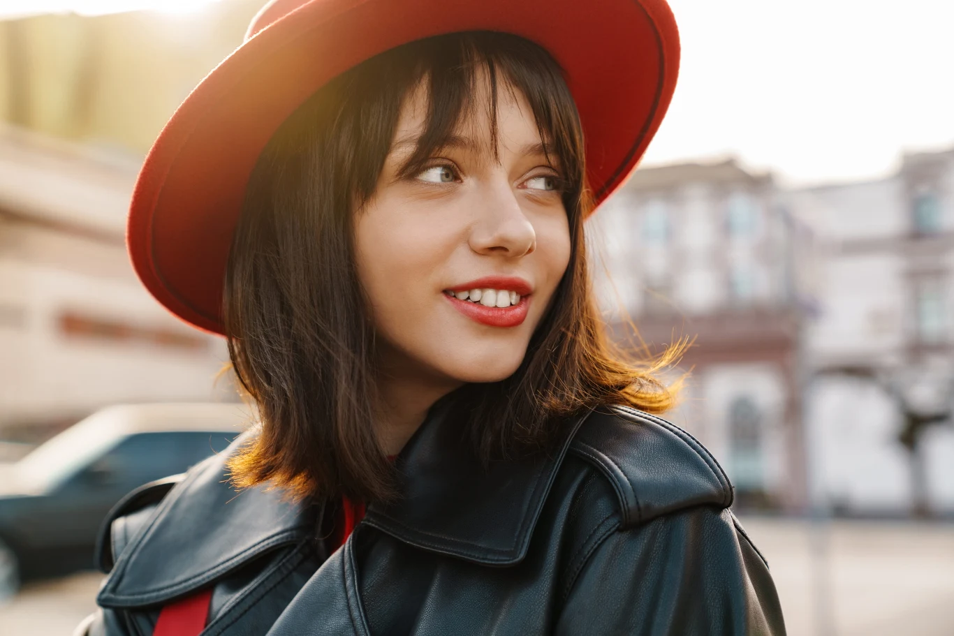 Whisper fringe to eteryczna grzywka, którą pokochały gwiazdy Kobieta z whisper fringe, krótkimi ciemnymi włosami, w czarnej kurtce i czerwonym kapeluszu patrzy w bok