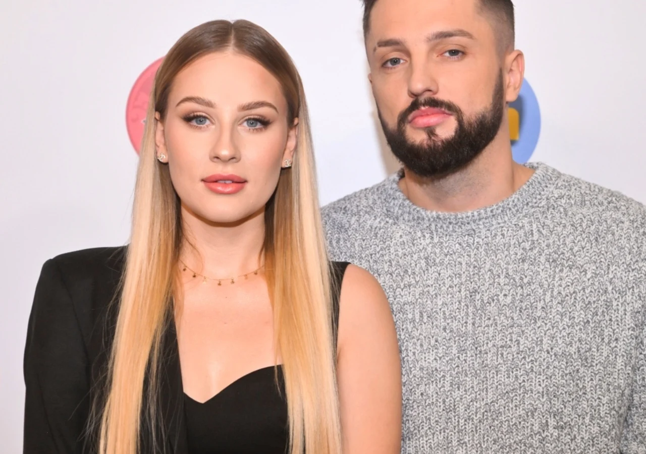 Andziaks, Luka Andziaks i Luka pozują razem do zdjęcia. Influencerka w czarnej marynarce obok swojego partnera w jasnoszarym swetrze.