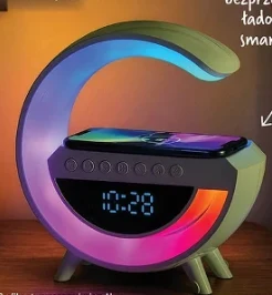 Zegar z lampką i możliwością bezprzewodowego ładowania smartfona Cyfrowy budzik w kształcie półksiężyca z podświetleniem LED, wyświetlaczem godziny oraz miejscem do ładowania smartfona na górze.