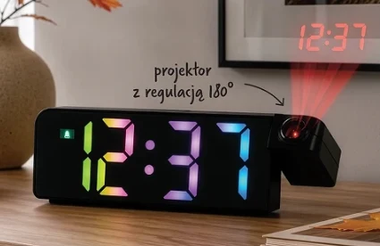 Budzik RGB z projektorem kosztuje 39,99 zł Cyfrowy zegar z kolorowym wyświetlaczem LED i projektorem czasu skierowanym na ścianę, ustawiony na drewnianym blacie obok wazonu i obrazu.
