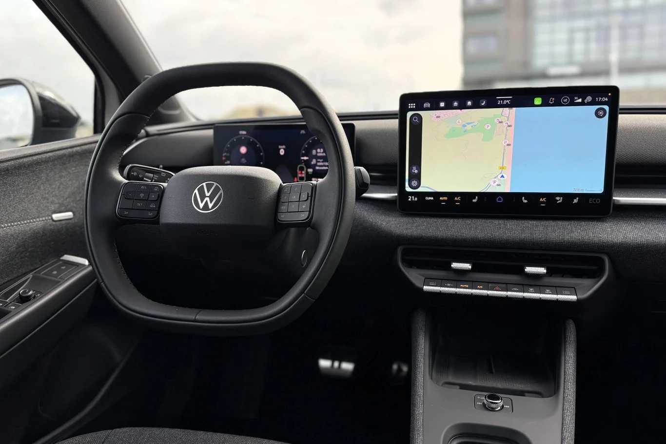 Kierownica Volkswagena, cyfrowy zestaw wskaźników oraz duży ekran systemu multimedialnego z wyświetloną nawigacją.