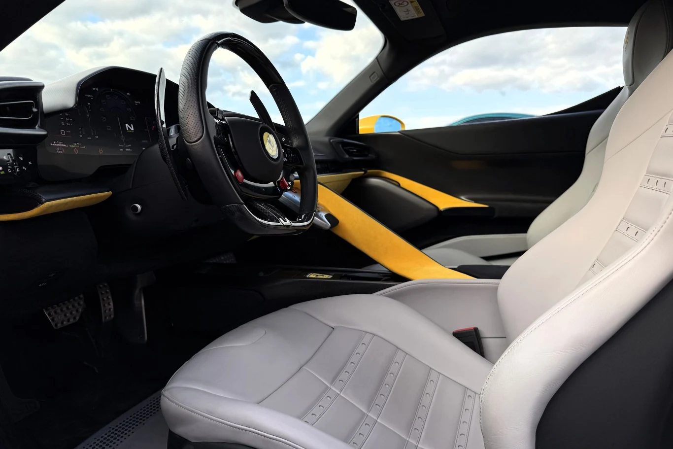 Ferrari 849 Testarossa ma bardzo wygodne fotele, ale w trybie Race z pewnością poczujemy nawet najmniejszą nierówność nawierzchni. Luksusowe wnętrze sportowego samochodu z jasnoszarymi skórzanymi fotelami, sportową kierownicą i ozdobnymi żółtymi wstawkami na desce rozdzielczej oraz drzwiach.