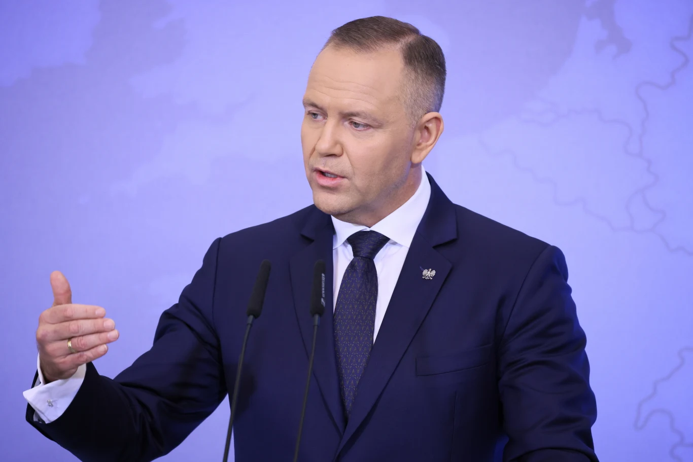 Prezydent Karol Nawrocki stawia warunki przed zaprzysiężeniem Berka Prezydent Karol Nawrocki w garniturze przemawia do mikrofonów na tle jasnej mapy podczas konferencji.