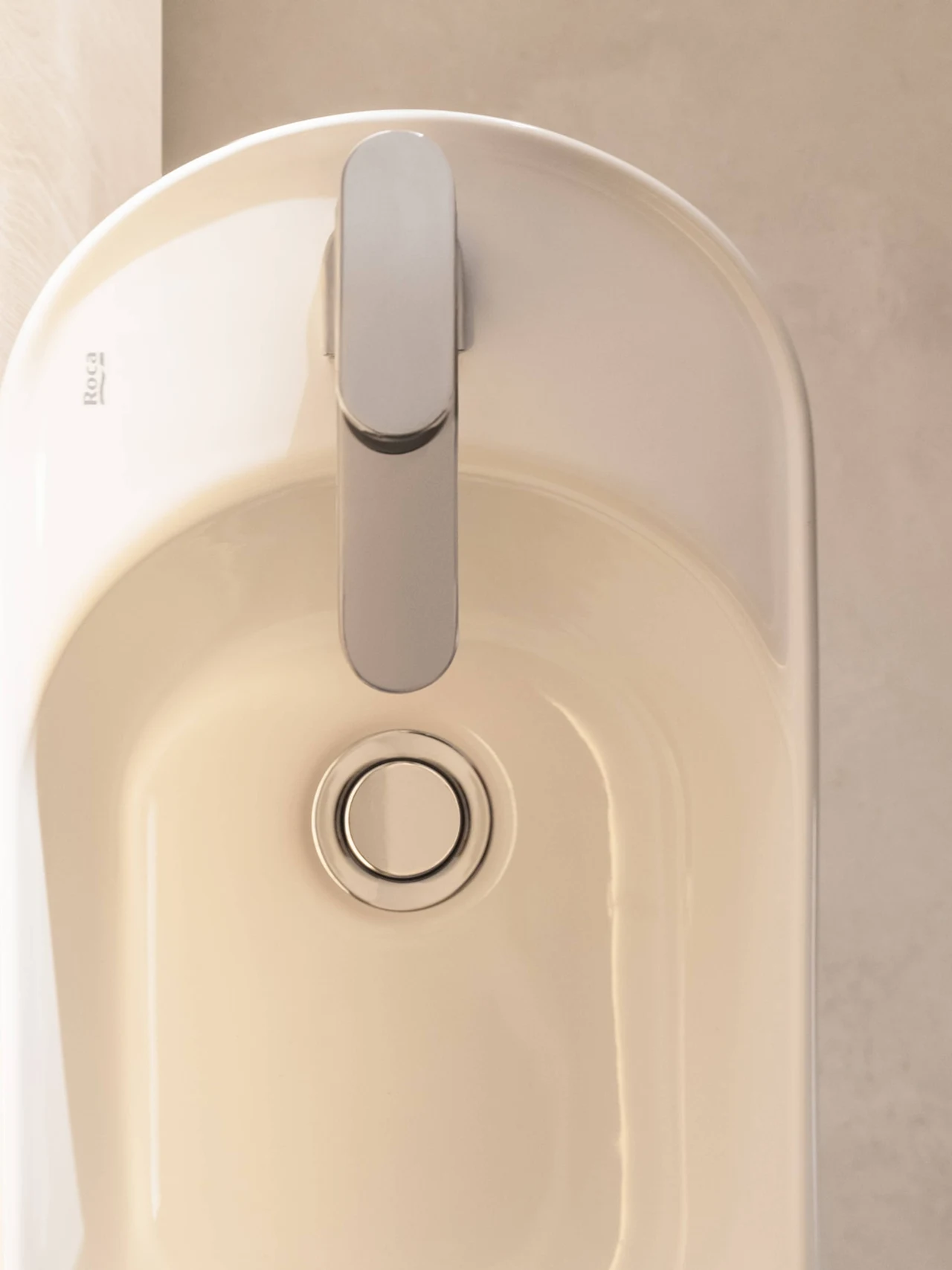 Kolekcja Meridian od Roca Minimalistyczna biała umywalka z nowoczesną chromowaną baterią oraz okrągłym odpływem centralnie umieszczonym na dnie.