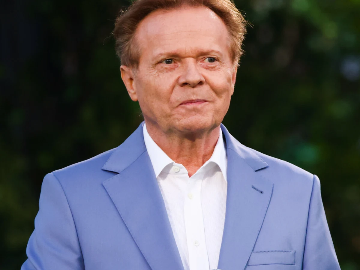 Michał Bajor Michał Bajor w jasnoniebieskiej marynarce i białej koszuli na zielonym tle.