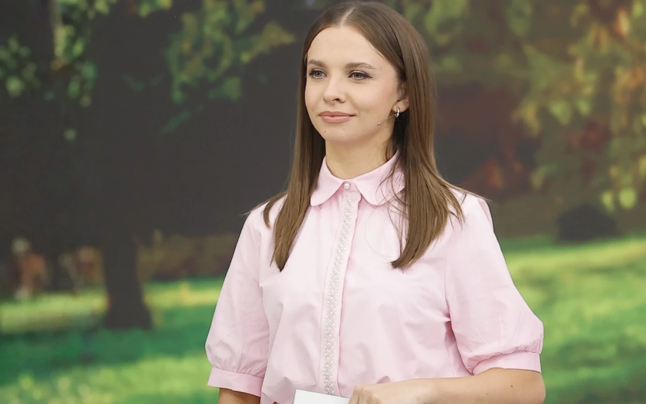 Ola Filipek w różowej koszuli poprowadziła "halo tu polsat" 19 września Kobieta z prostymi, brązowymi włosami ubrana w jasnoróżową koszulę z kołnierzykiem, trzymająca kartkę papieru, stoi na tle rozmytego obrazu zielonego parku.