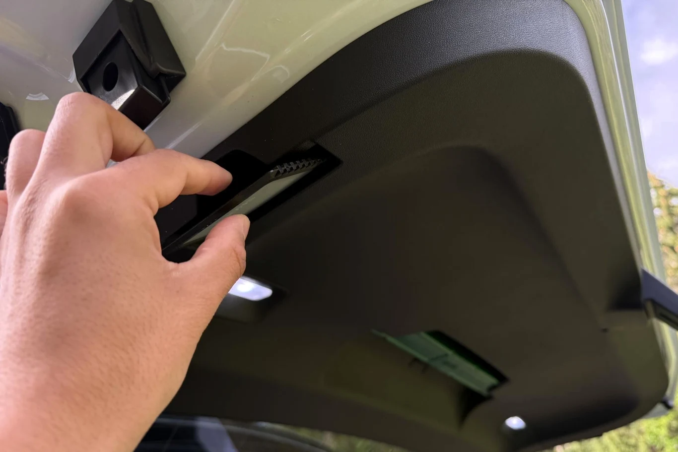 Skoda Peaq jest wyposażona w rozwiązania Simply Clever, m.in. skrobaczkę do szyb w klapie bagażnika. Dłoń sięgająca po uchwyt na wewnętrznej stronie klapy bagażnika samochodu.