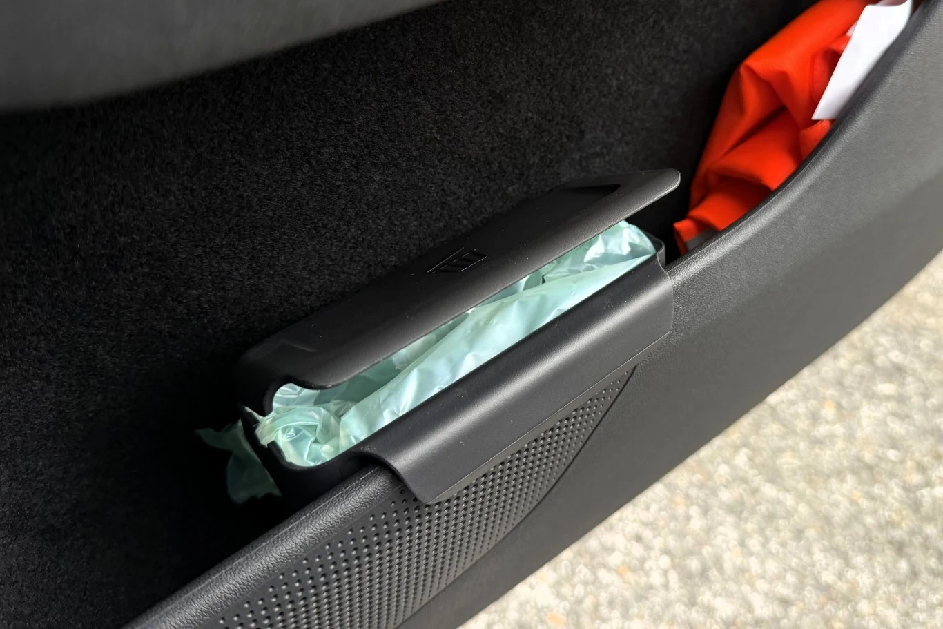 Wśród praktycznych rozwiązań Skoda Peaq oferuje choćby kosz na śmieci. Pojemnik z chusteczkami umieszczony w bocznej kieszeni drzwi samochodu, obok czerwonego materiału.