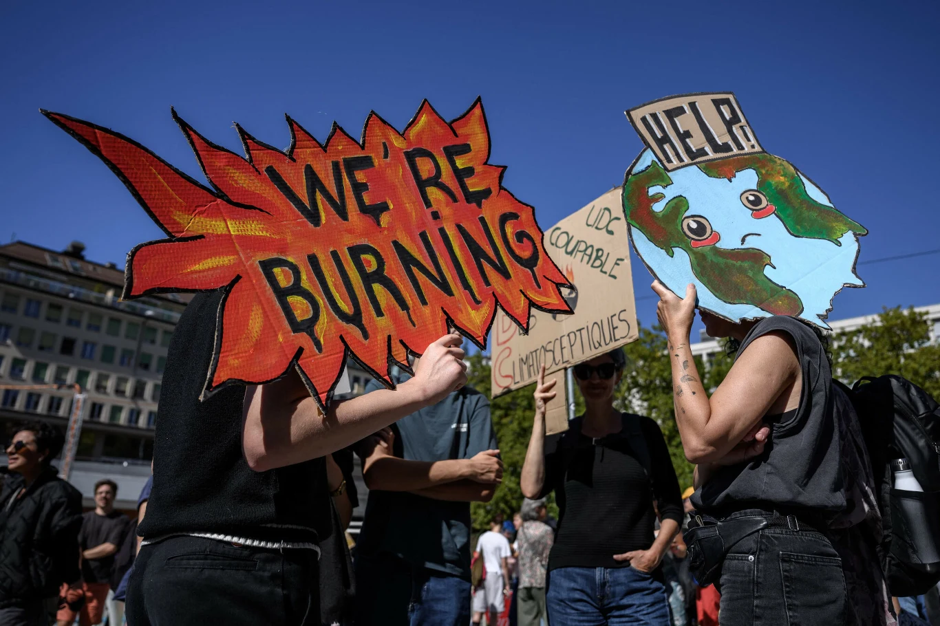 W Szwajcarii w weekend odbyły się protesty klimatyczne. "Płoniemy", "pomocy" - mówiły niektóre transparenty Grupa osób podczas protestu klimatycznego w Szwajcarii trzyma transparenty z napisami „WE’RE BURNING” i „HELP” oraz rysunkiem Ziemi.