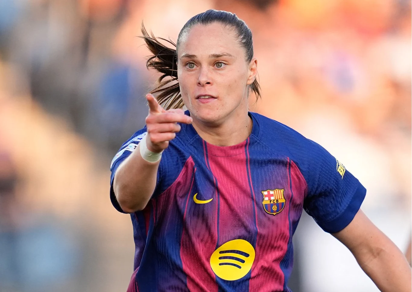 Piłkarka w stroju FC Barcelony z uniesioną ręką, skupiona podczas meczu.