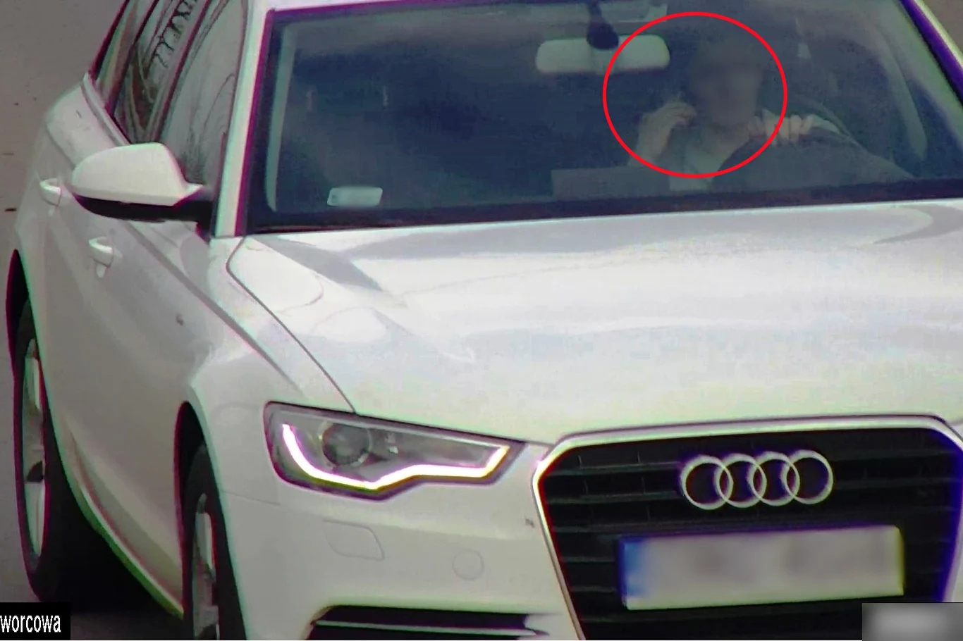 Kierowca przyłapany podczas policyjnej akcji pod kryptonimem "Łapki na kierownicę" Kierowca białego audi podczas jazdy trzyma telefon przy uchu, akcja policyjna "Łapki na kierownicę"