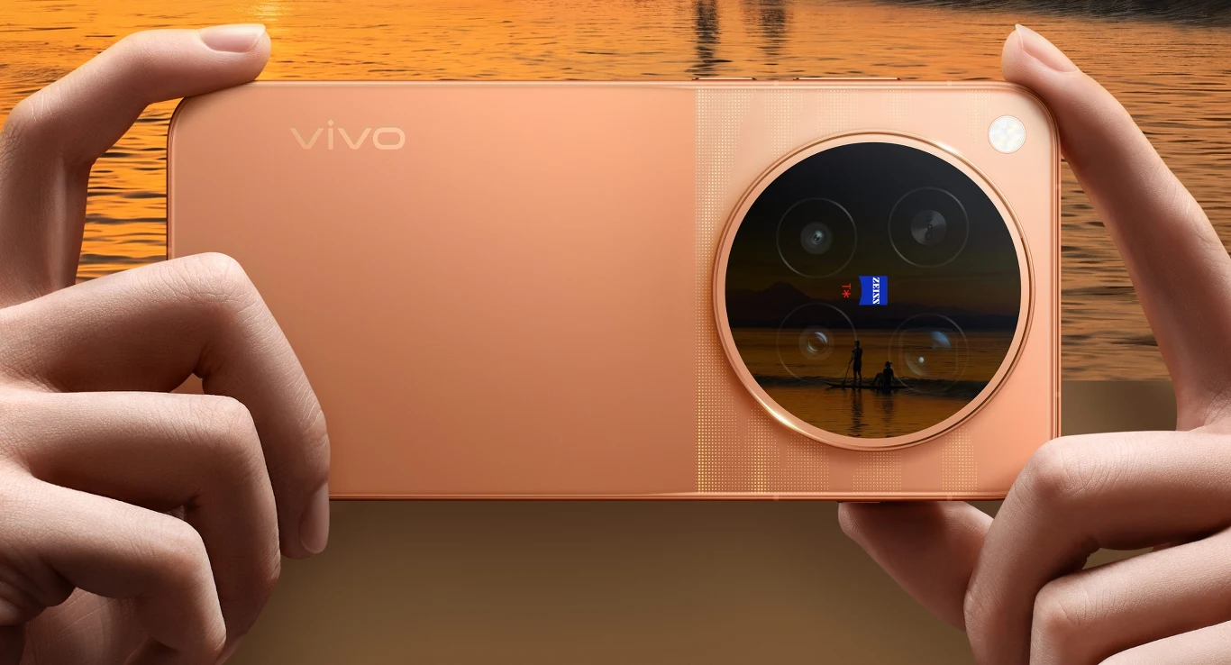 Premiera X500 Pro i X500 Pro Max. Kiedy w Polsce? Vivo X500 Pro w kolorze brzoskwiniowym, trzymany oburącz, z dużą wyspą aparatów odbijającą jezioro o zachodzie.