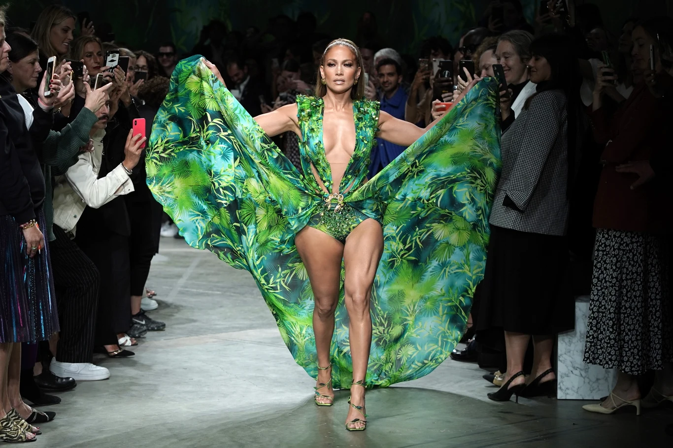Jennifer Lopez od lat mocno związana jest ze światem mody, a Mediolan ma dla niej wyjątkowe znaczenie. Gwiazda pojawiła się na wybiegu pokazu Versace podczas Tygodnia Mody w Mediolanie, wiosna/lato 2020 w słynnej sukni Modelka w efektownej zielonej sukni z tropikalnym wzorem idzie środkiem wybiegu, otoczona przez fotografujących i podziwiających ją widzów.