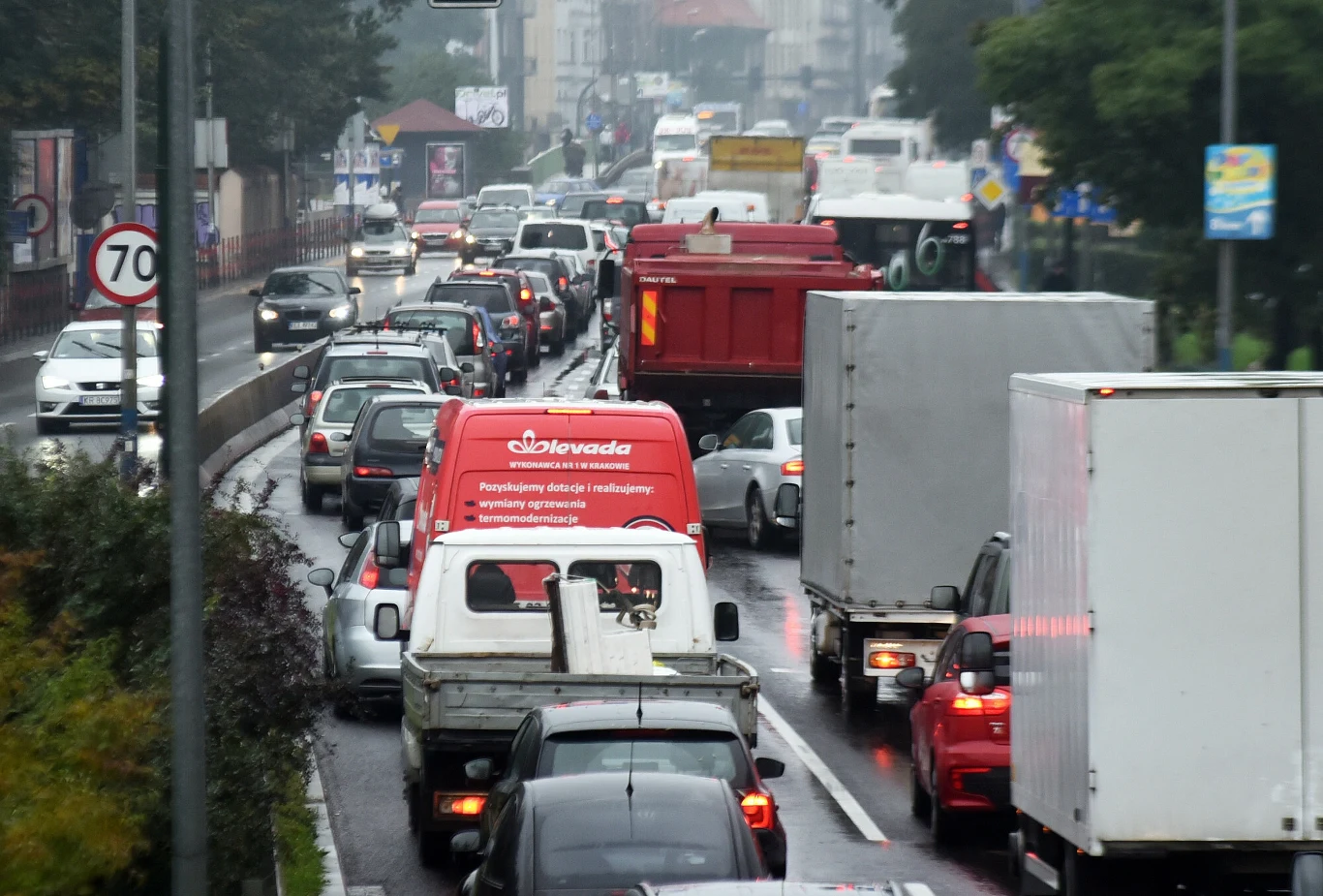 Kierowcy zwykle z rezerwą podchodzą do darmowej komunikacji i korki na ulicach wcale nie są mniejsze Ulica w mieście z wieloma samochodami, furgonetkami i ciężarówkami stojącymi w korku po deszczu