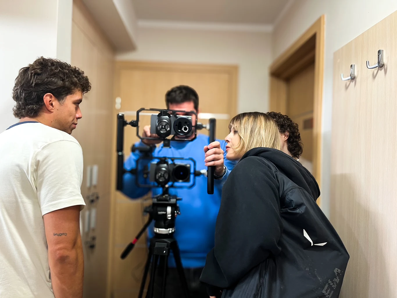 Damian Stefańczyk, dokumentalista, twórca internetowy, przy tym projekcie pełni funkcję mentora Ekipa filmowa z profesjonalną kamerą podczas nagrywania sceny, dwie osoby intensywnie omawiają szczegóły ujęcia w wąskim korytarzu.