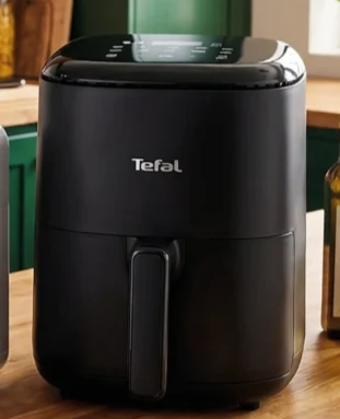 Air fryer Tefal Czarna frytkownica beztłuszczowa marki Tefal ustawiona na drewnianym blacie kuchennym.