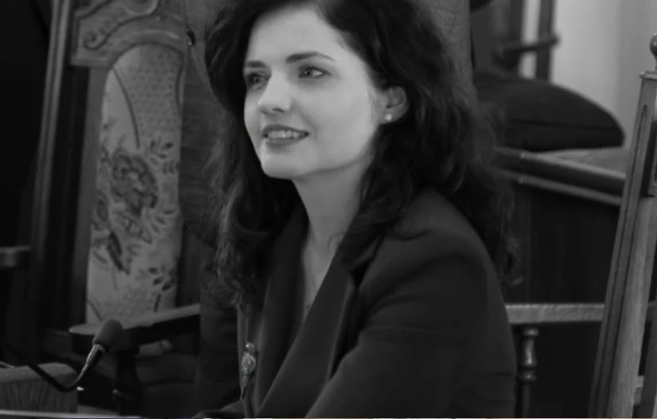 Nie żyje Katarzyna Zaczek Kobieta z długimi, ciemnymi włosami siedzi przy stole i uśmiecha się, ubrana w elegancką marynarkę, w tle widoczne ozdobne krzesło.
