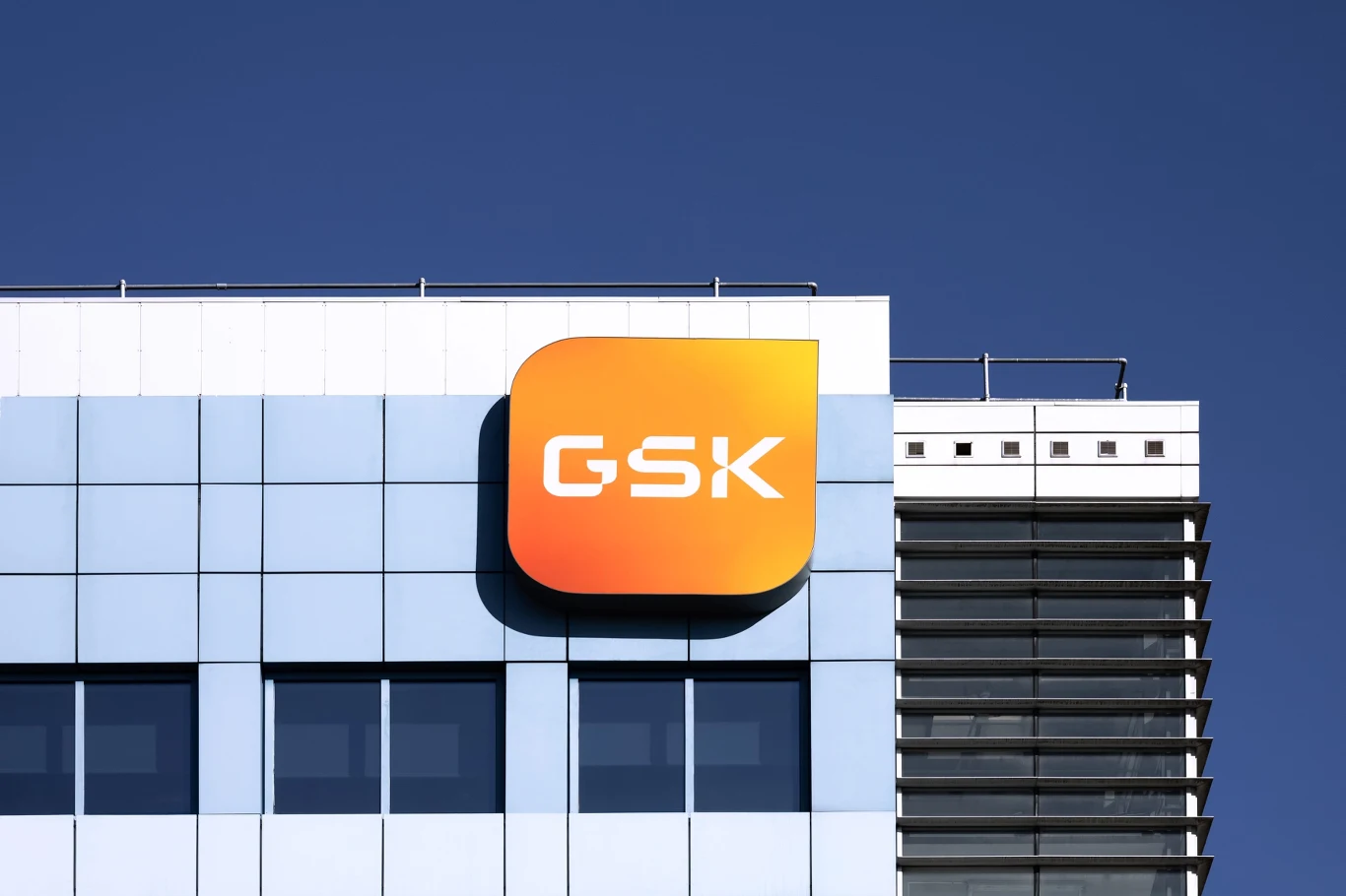Ponad 500 osób zatrudnionych w oddziale GSK w Poznaniu może stracić pracę. Zdj. ilustracyjne Logo GSK na szklanej elewacji biurowca w Poznaniu, widoczne na tle nieba.