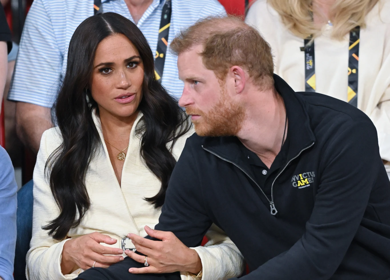 Przyjaciółka Meghan wyjawiła kulisy jej przeprowadzki Kobieta w białej marynarce i mężczyzna w czarnej bluzie z logo Invictus Games siedzą obok siebie, rozmawiając w skupieniu.