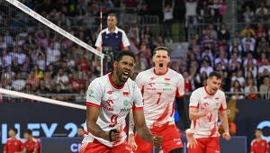 Zawodnicy polskiej reprezentacji siatkówki wyrażający radość po zdobyciu punktu w trakcie meczu, ubrani w biało-czerwone stroje sportowe, otoczeni dopingującą publicznością na trybunach.