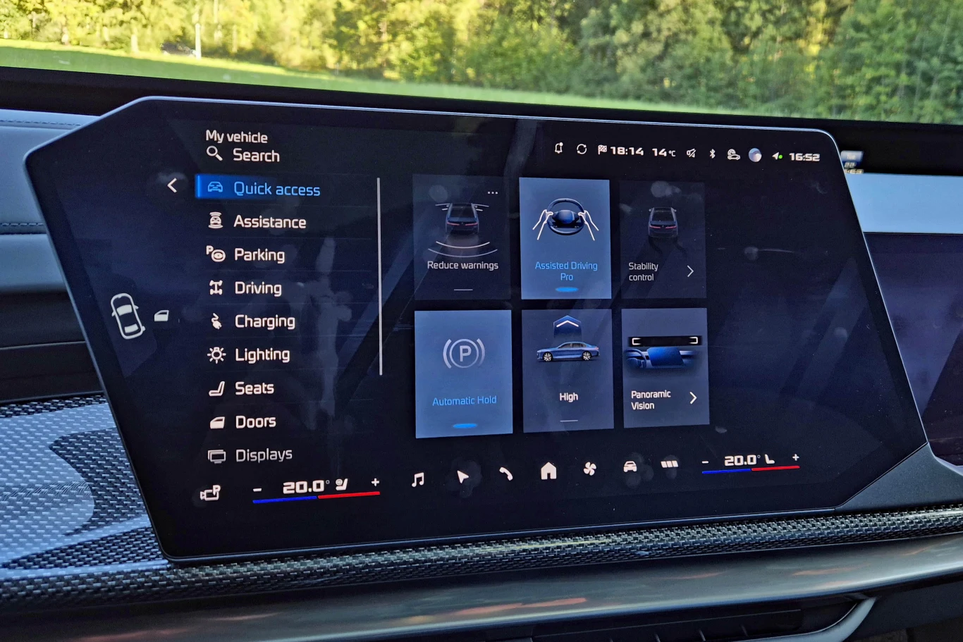 System w odświeżonym BMW serii 7 ma bardzo rozbudowane menu, ale jego obsługa jest łatwiejsza niż w poprzedniku Dotykowy ekran systemu multimedialnego samochodu z wyświetlonym menu szybkiego dostępu do ustawień jazdy, asystenta parkowania, świateł, siedzeń i ekranu głównego, z widocznymi ikonami opcji i temperaturą klimatyzacji po obu stronach panelu.
