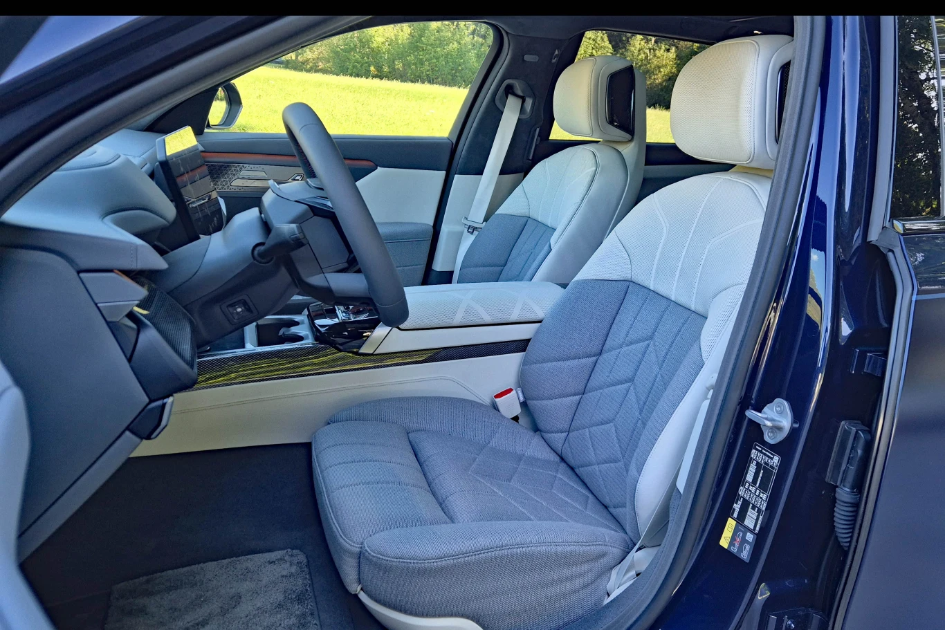 Nie dla każdego skórzana tapicerka jest synonimem luksusu - dla takich osób BMW przygotowało wykończenie, które łączy skórę z wełną i kaszmirem Przestronna przednia część nowoczesnego samochodu z jasnymi, komfortowymi fotelami i zaawansowaną konsolą środkową z dużym ekranem dotykowym.