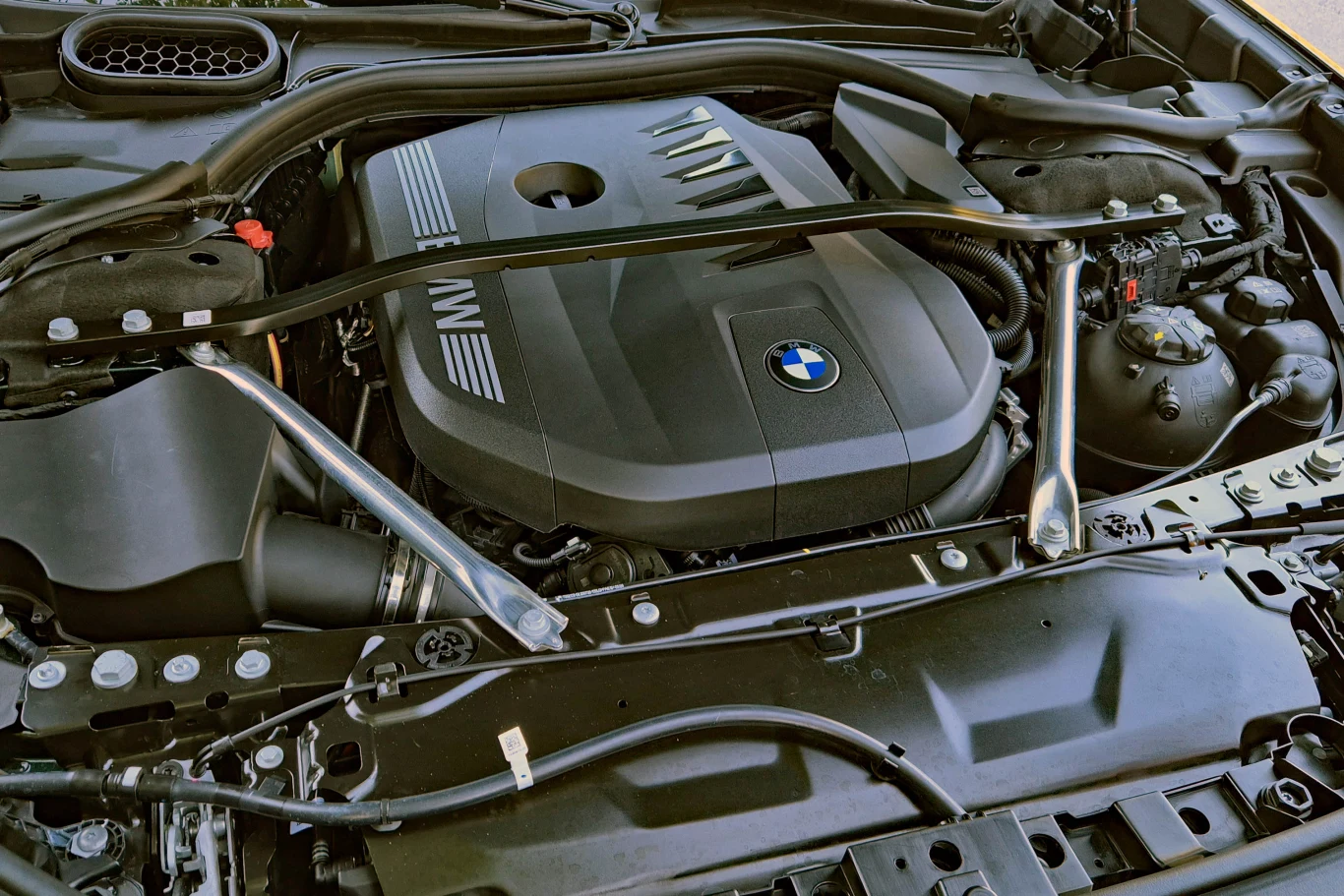 Rzędowy, sześciocylindrowy silnik w nowym 740 brzmi zaskakująco rasowo i zapewnia naprawdę dobre osiągi Silnik BMW z osłoną wyposażoną w logo marki oraz elementy układu dolotowego i wzmocnienia strukturalne pod maską.